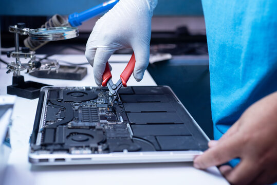 IT Technician working on Apple MacBook Pro with cutters and magnifying glass